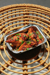 Homemade baked chicken breast in the aluminum foil box served on the table barbeque grill. Selective focus. 