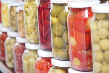 Colorful jars of preserved vegetables lined on a wooden shelf