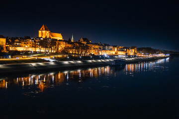 Obraz premium Magical night overlooking the illuminated Old Town of Torun, Poland by the Vistula River