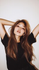 Obraz premium Young woman with long light brown hair in black top with hands behind head