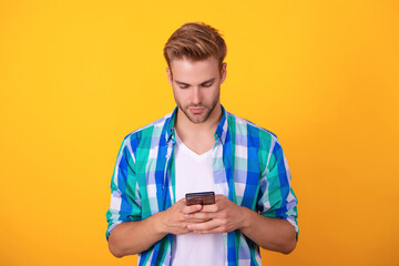 Phone chat. Mobile communication. Communication. Man texting on smartphone isolated on yellow. Millennial man using phone for messaging. Chatting online. Man texting on smartphone