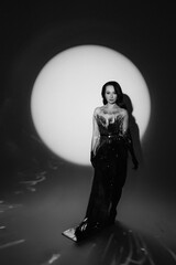 A woman in a metallic dress poses under a dramatic spotlight. Her confident stance and artistic lighting convey glamour, mystery, and high fashion. Perfect for editorial, luxury, and cinematic themes.