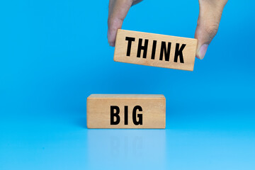 male hand put wooden blocks with think big word isolated on blue background