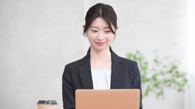 オフィスで働くパソコンをタイピングするスーツを着た若い20代の女性の正面の動画