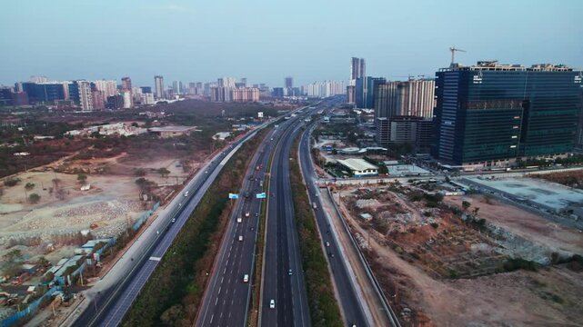 Outer ring road with solar cycle track and buildings at khanapur, financial district, nanakramguda, hyderabad, telangana, india. day time, moving down, tilt up, drone shot, 4k.