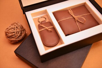 New natural brown leather wallet and key ring in black box on beige background