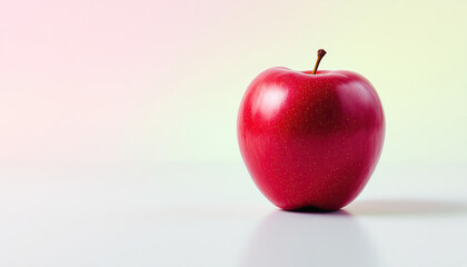 A single perfectly ripe red apple sits on a light surface