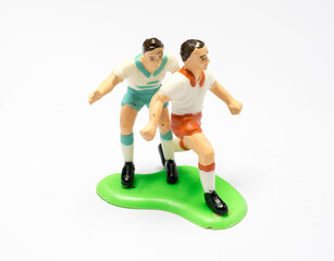 A soccer player toy is playing football.