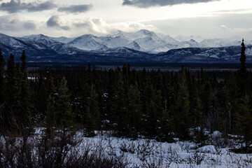 Sun lighting clouds and top of mountain in Alaska