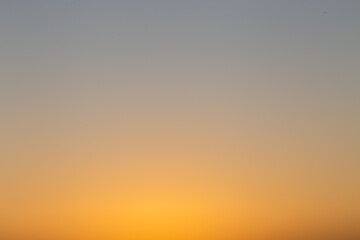 A soft, abstract gradient of warm golden and gray tones, resembling a blurred sunset or sky