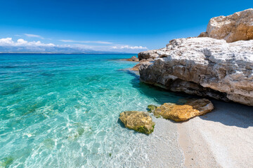 Crystal clear turquoise water and rocky coastline under bright sky