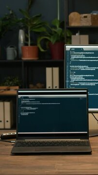 Vertical no people shot of two coding screens on digital devices at working table at office