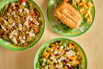 Assorted fresh salads and sandwich on a wooden table