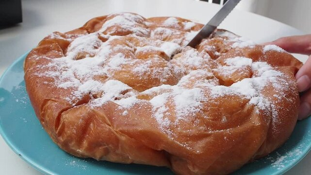 Freshly baked chocolate-filled ensaimada topped with powdered sugar on a blue plate