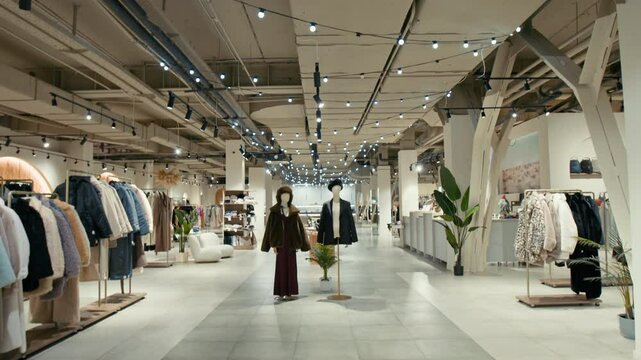 No people tilt down view of well-lit retail space featuring neatly arranged clothing racks on either side of wide aisle with two mannequins displaying fashionable outfits