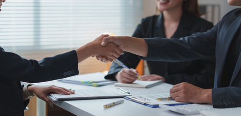 Businesspeople shaking hands after signing contract in office meeting
