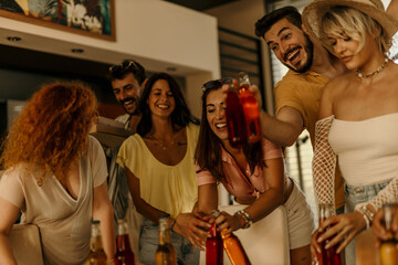 Group of cheerful friends enjoying drinks and pizza at a house party