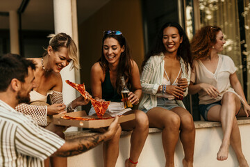 Friends eating pizza and drinking beer on a summer afternoon