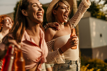 Obraz premium Cheerful people carrying pizza and drinks laughing together at a party