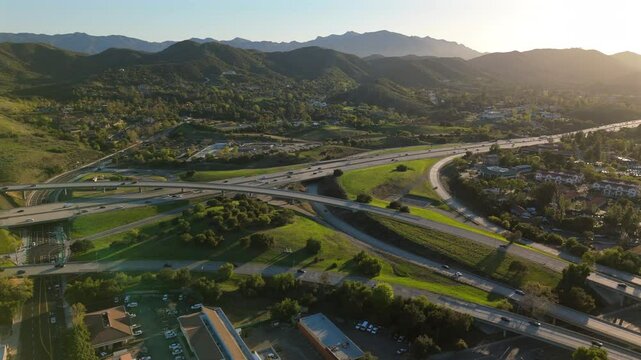 Aerial footage showcases a stunning Los Angeles California interchange, beautifully nestled amidst lush green mountains and vibrant suburban developments that contribute to the local ecosystem