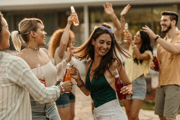Friends dancing and enjoying drinks together at a pool party