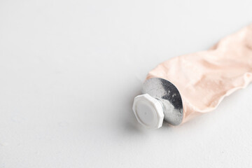 Crinkled beige cosmetic tube at grey background , minimalist style cosmetic product visuals.