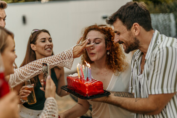 Group of friends surprising woman with birthday cake at a party