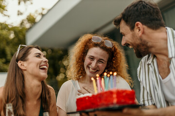 Group of friends surprising woman with birthday cake at a party