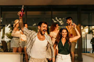Friends enjoying drinks at a rooftop party, celebrating and having fun