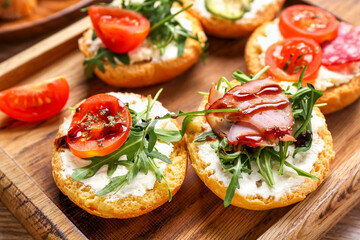 Wooden board with tasty sandwiches, closeup