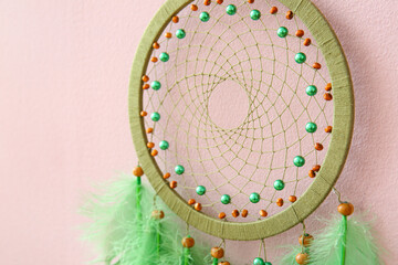 Dream catcher hanging on pink wall, closeup
