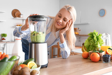 Mature woman making healthy smoothie with blender in kitchen