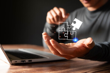 Businessman using laptop with jigsaw icons for problem solving concept and leadership strategy,...