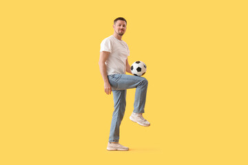 Fototapeta premium Man playing with soccer ball on yellow background