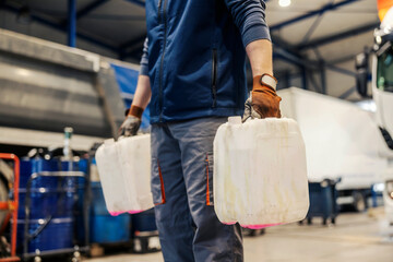 Cropped picture of worker carrying empty canisters at auto mechanic workshop.