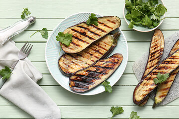 Plate with delicious grilled eggplants and parsley on green wooden background