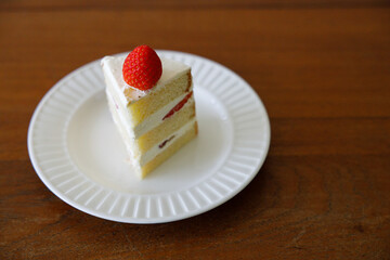 Freshly baked homemade strawberry shortcake pastry on white ceramic plate on wooden table background.