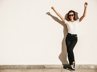 Portrait of beautiful model in sunglasses. Female dressed in summer white T-shirt and jeans. Trendy...