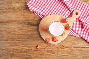 Glass of tasty strawberry smoothie on wooden background