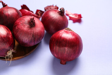 Plate with fresh red onions on blue background