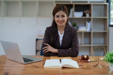 female attorney advisor at a law firm reviews legal documents at her desk equipped with a laptop notebook and scales of justice in the office