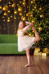 Happy little girl in a fancy dress dancing in a room with new year decor. 