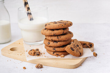 Tasty cookies with chocolate chips and glass of milk on white background