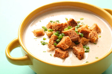 Pot of tasty cream soup with croutons on turquoise background