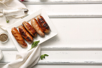 Plate of tasty grilled sausages on white wooden background