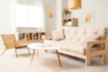Blurred view of living room interior with white sofa, armchair and coffee table