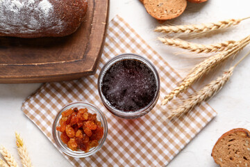 Glass of tasty kvass and raisins on white background