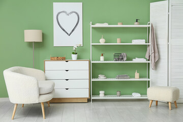 Modern shelf unit with white sofa and folding screen near green wall