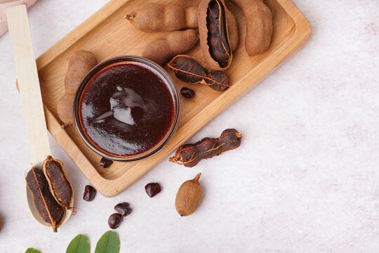 Bowl with tasty tamarind jam and fruits on white background