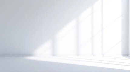 Obraz premium A bright, minimalistic interior space with white walls and large windows casting soft shadows on the floor.